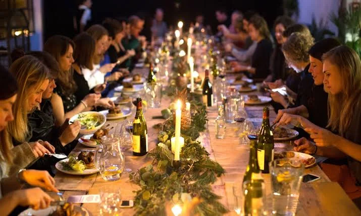 Guests sharing a long candlelit dinner table