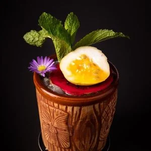 Tiki cocktail with mint and an edible flower